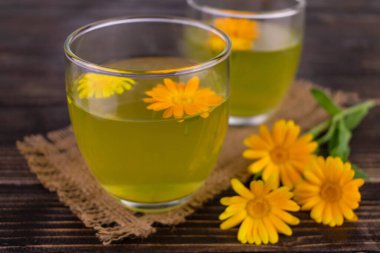 Koyu ahşap arka planda, kadife çiçeklerinden iki bardak çay..