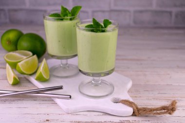 Beyaz ahşap arka planda iki kireç ve nane likörü..