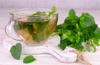 Mint tea in a transparent cup on a white wooden board.Close-up.