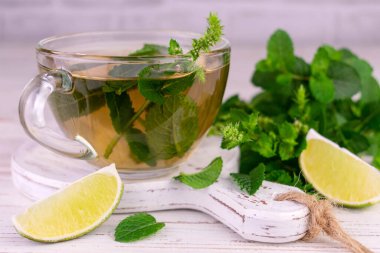 Mint tea in a transparent cup on a white wooden board.Close-up.