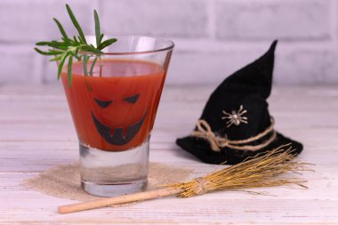 Halloween drink idea. Freak Monster Tomato Juice Cocktail. Jack-o-lantern face on a glass.