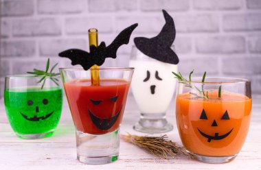 Different drinks for Halloween in glasses decorated with scary faces.