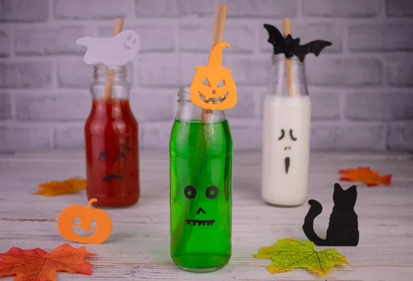 Drinks in bottles with monster faces. Jack-o-lantern face on glass. Halloween drinks.