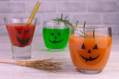 Different drinks for Halloween in glasses decorated with scary faces.