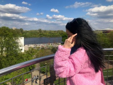 Wisla Nehri manzaralı Varşova Üniversitesi Kütüphanesi 'nin çatısındaki pembe ceketli genç bayan.