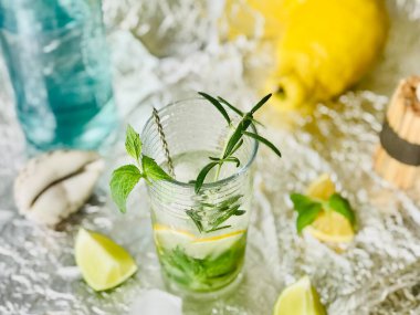 Soğuk limonlu içeceğe biraz buz küplü alkol eklenebilir ve çelik zemin üzerinde mumlarla nane şekeri.