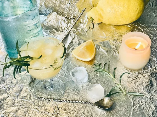 冷たいレモンドリンクに氷のキューブとミントと一緒にいくつかのアルコールを追加することができますキャンドルを背景に鋼 — ストック写真