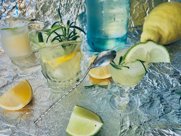 Cold lemon drink into which one can add some alcohol with ice cubes and mint on steel background with candles