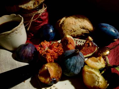 Kelebekli kahvaltı çeşidi ve erik, incir, ev yapımı ekmek, incir reçeli ve kahve gibi meyveler. Sadece doğal ışık kullanılır.