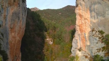 İnsansız hava aracı iki yüksek kayanın arasından yükseliyor. Dağların panoramik manzarası
