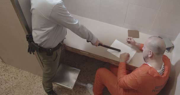 Gardien de prison avec matraque en caoutchouc dans ses mains fait prisonnier écrire des aveux — Video