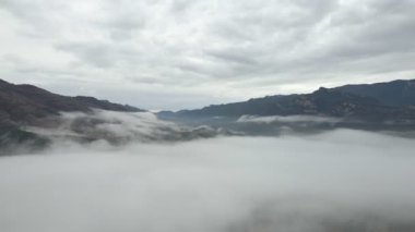 Bulutların üstünde karlı tepeleri olan yüksek dağlar, hava manzarası