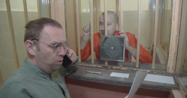 Advokaten pratar i telefon framför fången.. — Stockvideo