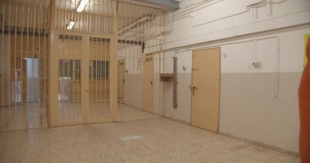 Тюремный надзиратель ведет заключенного к двери — стоковое видео