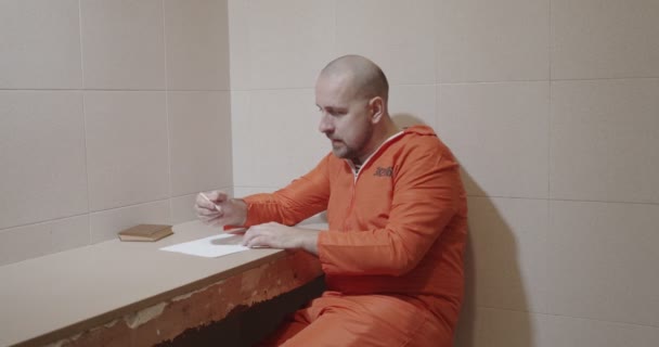 Gefängniswärter nähert sich einem Häftling beim Schreiben eines Briefes. — Stockvideo