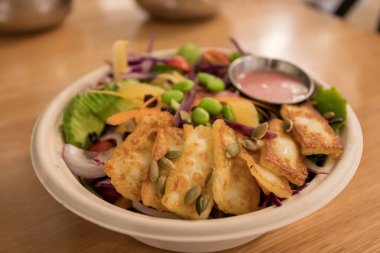 A fresh tossed Lebanese style salad on a wood table with fresh potato ladki.