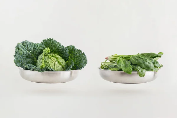 Minimal fresh green leafy vegetable scene with kale and spinach isolated on pastel beige background. Natural source of vitamins K, C and A. Nutrient rich food idea. Organic, raw, healthy food concept.