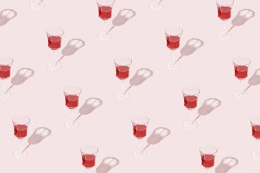 Pastel pembe arka planda izole edilmiş kırmızı şaraplı şarap kadehlerinden oluşan en küçük şablon. Parti, şarap dükkanı ya da şarap tatma konsepti için iç. Güneş, gölgeler ve yansımalar. Yaz Akdeniz dokusu. 