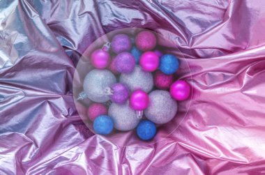 2022 Noel ağacı topları parlak holografik grafiklere karşı. Dairesel cam morfizm kopyalama uzayı olan minimum düz bir yer. Tebrik kartı konsepti. Pembe mor ve mavi yanardöner görsel efekt.