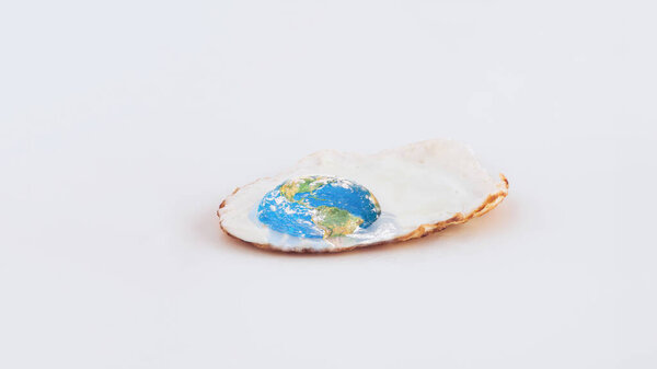 Fried poached egg and planet Earth on isolated pastel white background. Minimal abstract concept of dystopian future. Creative idea of global warming or climate changes card. World provided by NASA.