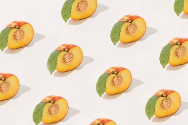 İzole edilmiş pastel bej arka planda taş ve yapraklardan oluşan yarı yarıya şeftali desenli yaz meyveleri. Doğa dekoratif bitki dokusu. Güneş ve gölgeler. Sağlıklı çiğ organik gıda kavramı.