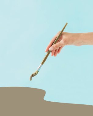 Genç kadınlar zeytin yeşiliyle pastel mavisi arkaplanı kuşkonmazdan yapılmış fırçayla boyarlar. Asgari soyut mutfak konsepti. Yaratıcı yemek yapmak ya da sağlıklı yemek yemek. Bahar ya da yaz sebzeleri.