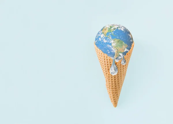 Planet Earth is melting in ice cream cone on isolated pastel blue background. Minimal abstract creative concept of warming, melting glaciers, pollutions. Anti-war idea. Dystopian climate change future. World provided by NASA.