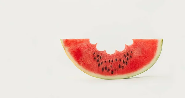 Slice of watermelon with cloud-shaped cut-out and drops of rain made of black watermelon seeds. Minimal abstract refreshing fruit scene. The idea of a summer downpour. Raw alkaline food concept.