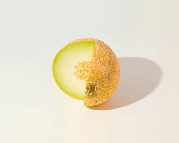 Minimal summer fruit scene made of cut sunlit melon on isolated pastel beige background. Sun and shadows. Abstract creative agriculture idea or raw food concept.