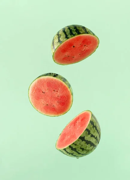 Fresh watermelon slices floating on isolated pastel green background. Minimal summer concept of hydration fruit, alkaline food or organic agricultural products. Source of lycopene and vitamin C.