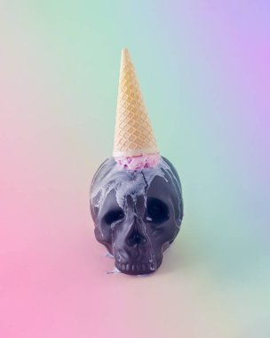 Tepetaklak olmuş bir külah dondurma damlatan siyah bir kafatası. İzole yanardöner arka plan. Korkunç Cadılar Bayramı partisi konsepti. Gökkuşağı gradyanı olan davet kartı.