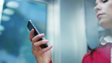 Asansörde cep telefonunuzu kullanarak iş kadını.