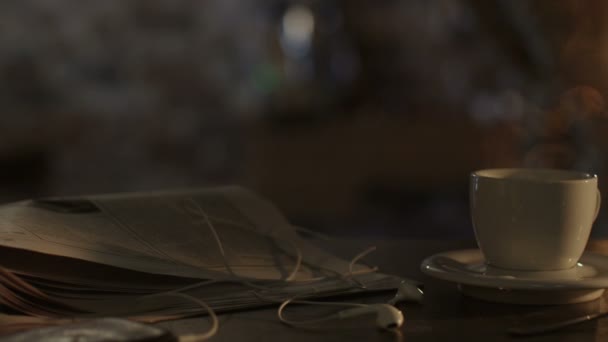 Tiro de taza de café y periódico en la mesa a la luz del sol de la mañana — Vídeos de Stock