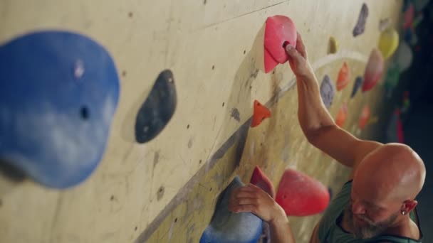 Escalador practicando en el muro de escalada interior — Vídeos de Stock