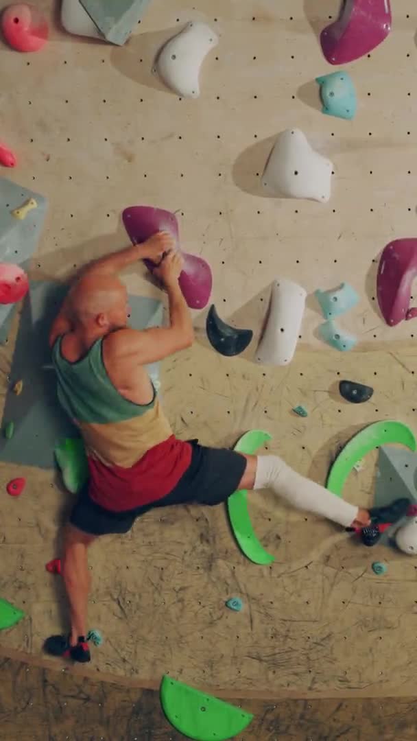 Atleta de metraje vertical practicando en la pared de escalada interior — Vídeos de Stock