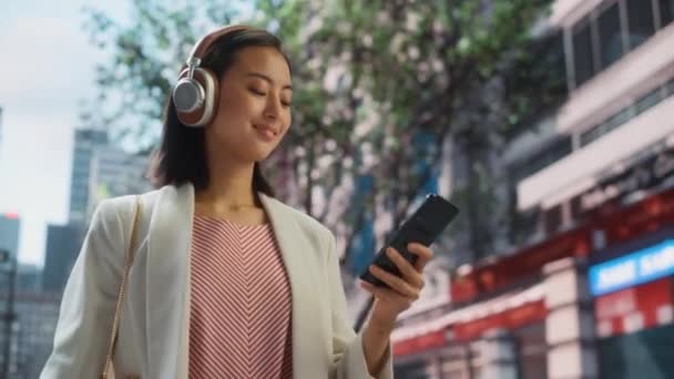 Japanska kvinnliga lyssnare musik på Smartphone på City Street — Stockvideo