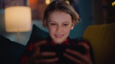 Genç çocuk evde akıllı telefondan oyun oynuyor.