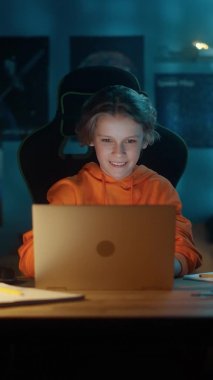 Evde Dizüstü bilgisayar kullanan genç bir çocuğun dikey portresi