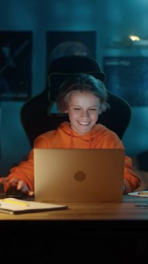 Evde Dizüstü bilgisayar kullanan genç bir çocuğun dikey portresi