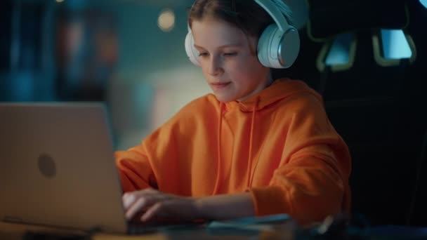 เด็กชายในหูฟัง ใช้คอมพิวเตอร์แล็ปท็อปที่บ้าน — วีดีโอสต็อก