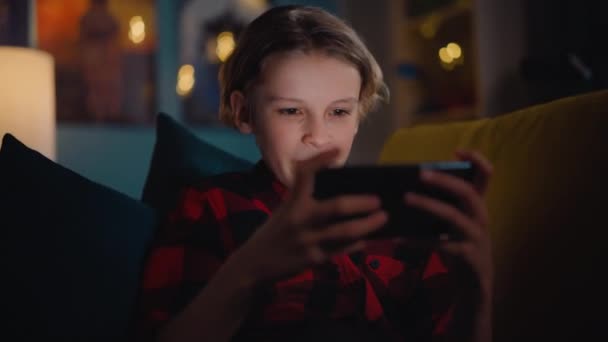 Νεαρό αγόρι παιχνίδι στο Smartphone στο σπίτι — Αρχείο Βίντεο