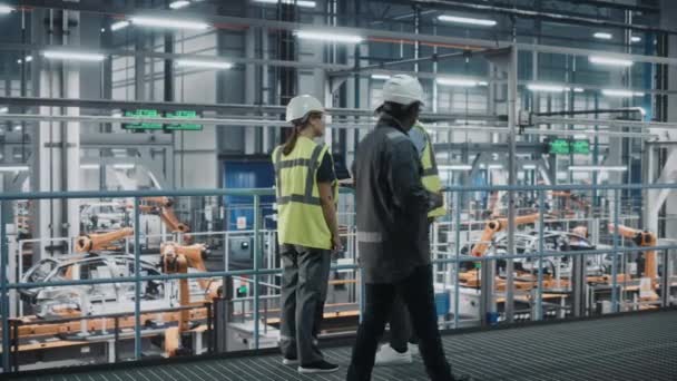 Kfz-Ingenieure sprechen in Autofabrik mit Laptop — Stockvideo