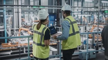 Otomotiv mühendisleri araba fabrikasında dizüstü bilgisayar kullanıyor.