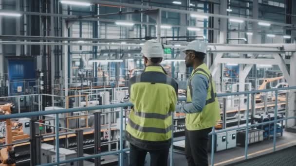 Engenheiros industriais conversando usando laptop na fábrica de carros — Vídeo de Stock