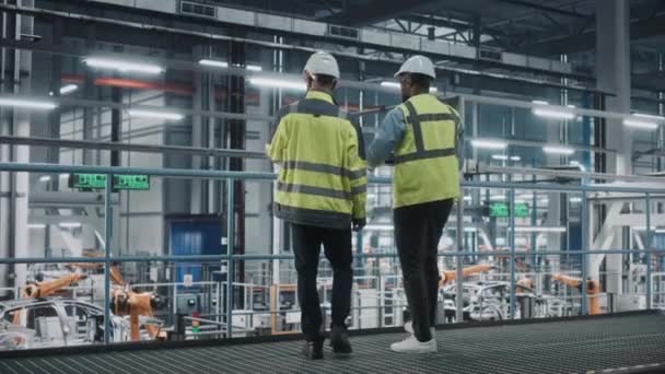 Industriingenjörer pratar med bärbar dator på bilfabriken — Stockvideo