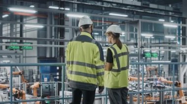 Otomotiv mühendisleri araba fabrikasında dizüstü bilgisayar kullanıyor.