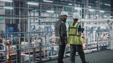 Otomotiv mühendisleri araba fabrikasında dizüstü bilgisayar kullanıyor.