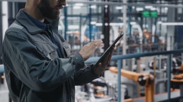 Инженер-мужчина работает над планшетом на автомобильном заводе — стоковое видео