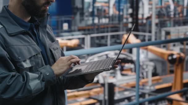Mandlig ingeniør arbejder på laptop på bilfabrikken – Stock-video