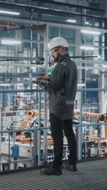 Dikey Portre Mühendisi Otomobil Fabrikasında dizüstü bilgisayarda çalışıyor.